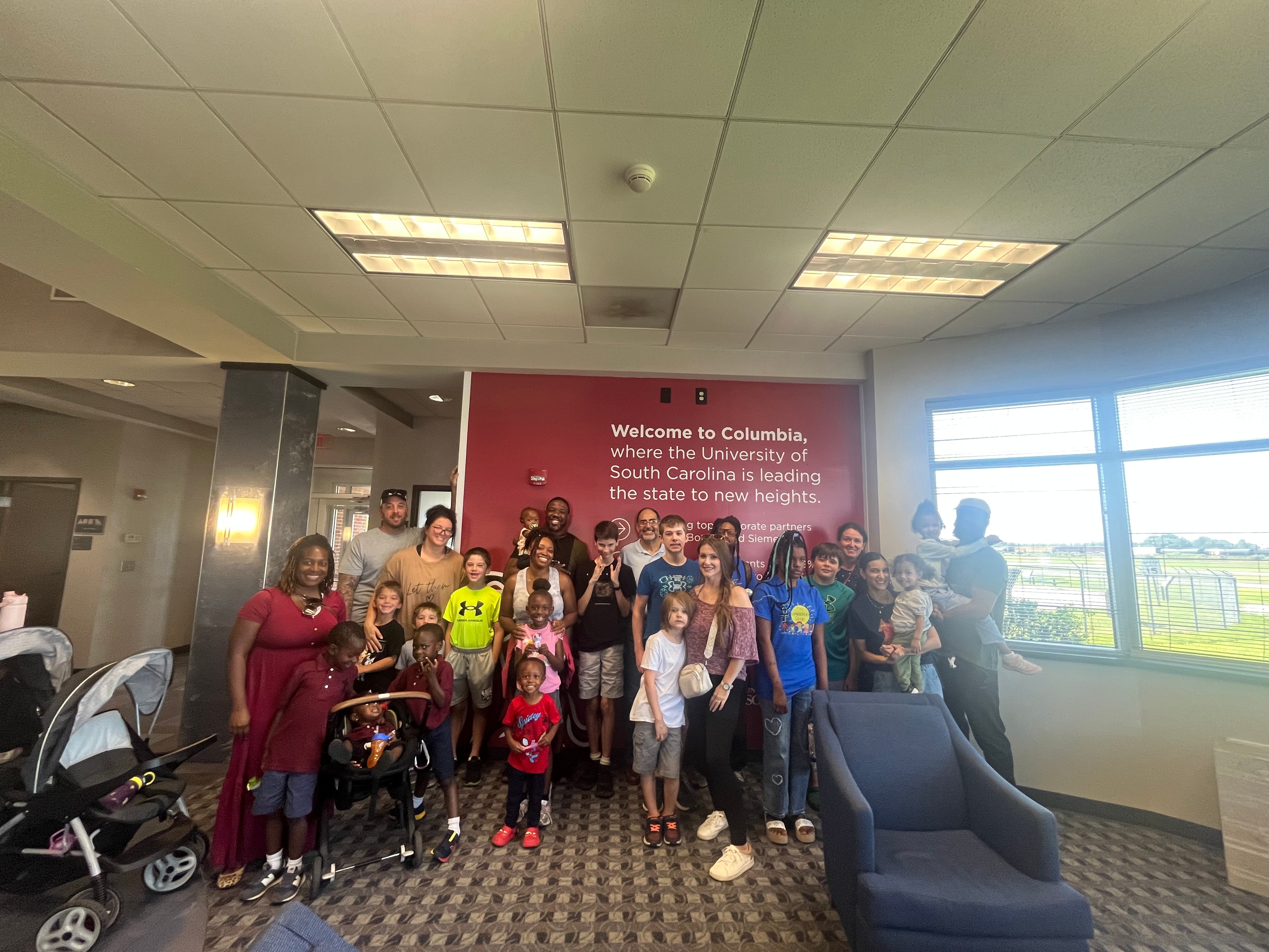 Full group photo of Ase co-op families inside the airport terminal