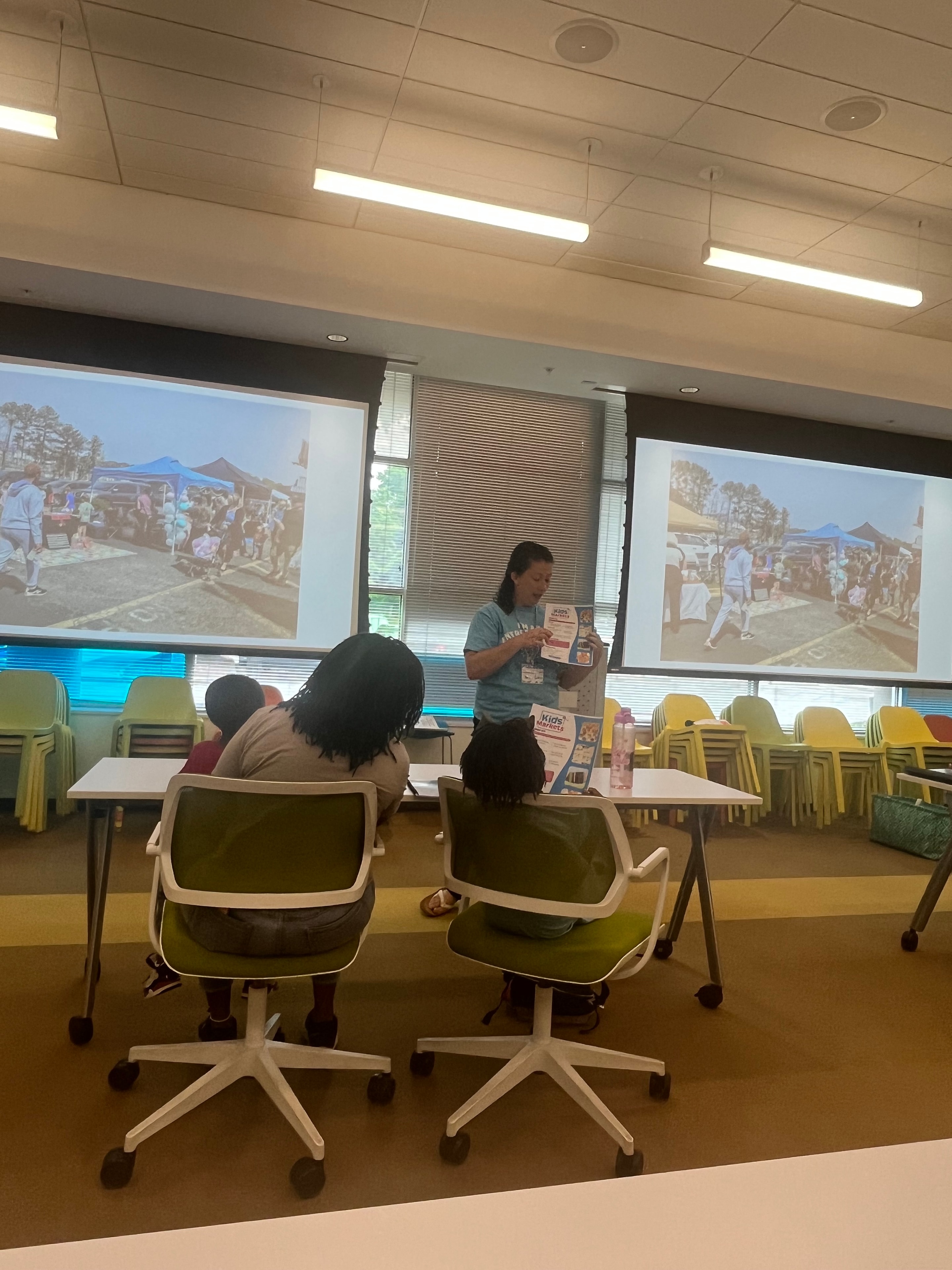 Students at the Kids Market Young Entrepreneurs event with a presentation on screen